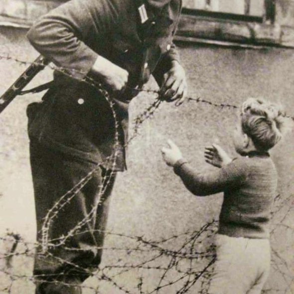German soldier seen going against a direct order to help a child cross the Berlin Wall to be with his family, 1961