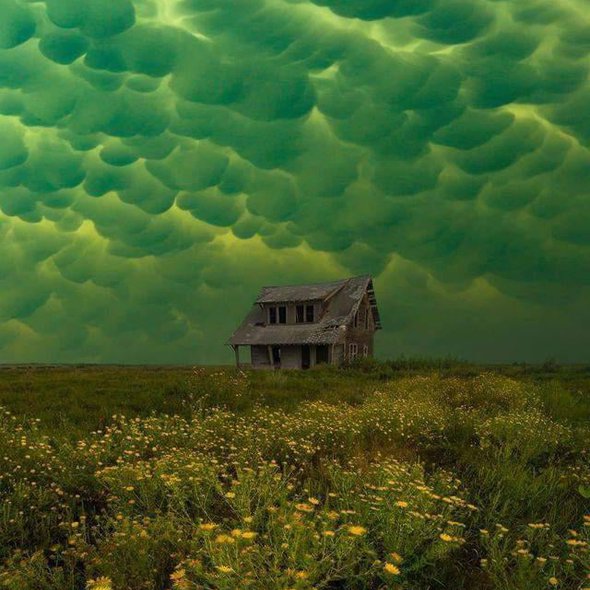 Green mammatus clouds, which usually precede a tornado, over an abandoned house.